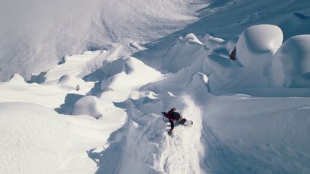 Travis Rice lands on powder snow as he goes down a mountain in Alaska.  (photo credit: Travis Rice, Inc)