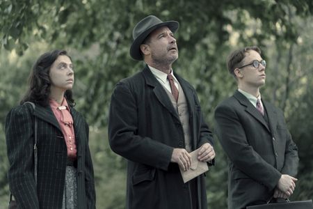 A SMALL LIGHT - Miep Gies, played by Bel Powley, Otto Frank, played by Liev Schreiber, and Jan Gies, played by Joe Cole, look up at Otto's old apartment as seen in A SMALL LIGHT. (Credit: National Geographic for Disney/Dusan Martincek)