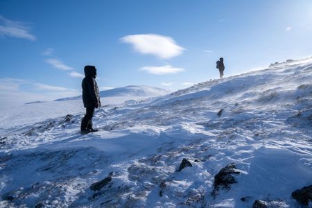 The crew stands on a snowy mountainside in the Brooks Range, Alaska, looking for Caribou.(National Geographic for DisneyEvan Vacek)