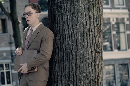 A SMALL LIGHT - Jan Gies, played by Joe Cole, hides behind a tree as seen in A SMALL LIGHT. (Credit: National Geographic for Disney/Dusan Martincek)