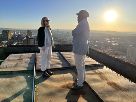 Mariana van Zeller and Ben discuss the world of scamming while on a rooftop in Johannesburg. (National Geographic for Disney)