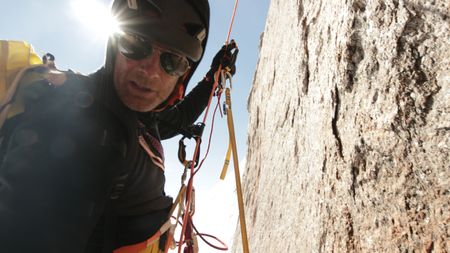 Professional alpinist Conrad Anker climbs a mountain in Queen Maud Land, in Antarctica. Anker looks at the camera lens with his sunglasses on.  (credit: National Geographic/Cedar Wright)
