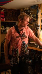Conrad Anker stands in his gear room holding climbing equipment as the film crew sets up the next shot.   (National Geographic/Elena Gaby)