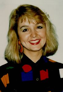 Jodi Huisentruit in the summer of 1993 wearing a multi-colored sweater, smiling at the camera. 