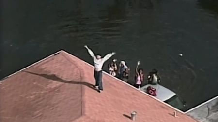 Stranded New Orleans residents stand in flood waters and on the roof of a flooded house and wave at a helicopter, hoping to be rescued in the aftermath of Hurricane Katrina in 2005. (Kurator/Tegna/WWL)