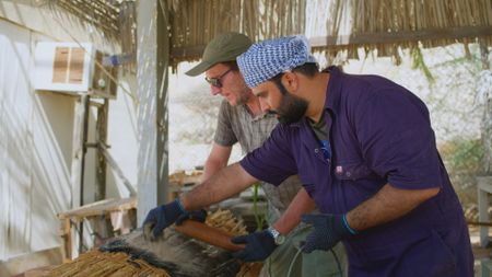 Allesandro Ghido and Ayaz Khalid Abulqader Al Zadjali strengthening the experimental boat they built with bitumena and sand in Qantab, Oman. (Windfall Films)