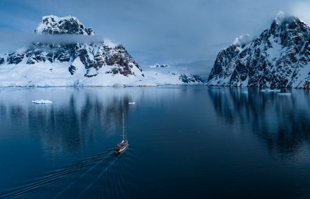 The Spirit of Sydney sailing into an inlet between two mountains in the Antarctic Peninsula. (credit: National Geographic/Bertie Gregory)